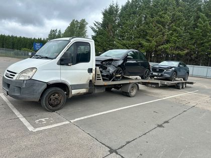 Accident-damaged car loaded on a Roadsist Auto flatbed in North Lanarkshire, with a second vehicle on the trailer behind