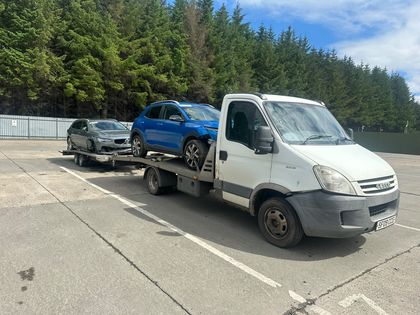 Two cars loaded for transport on a Roadsist Auto truck and trailer at the yard in Cleland